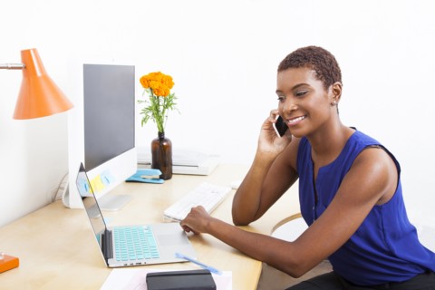 Black businesswoman talking on cell phone at office desk