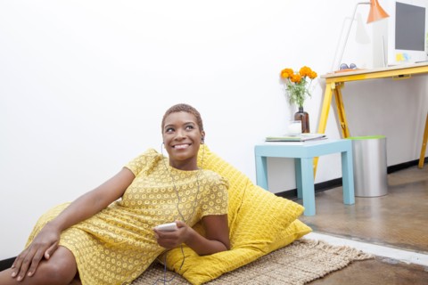 Black woman listening to mp3 player on floor