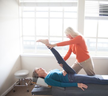 Caucasian chiropractor stretching leg of client
