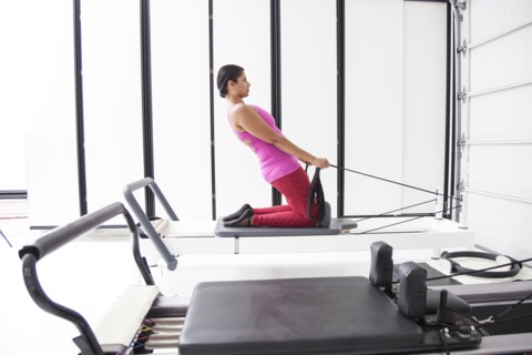 Asian woman using exercise machine in gymnasium