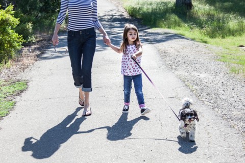 Mother and daughter walking puppy on path