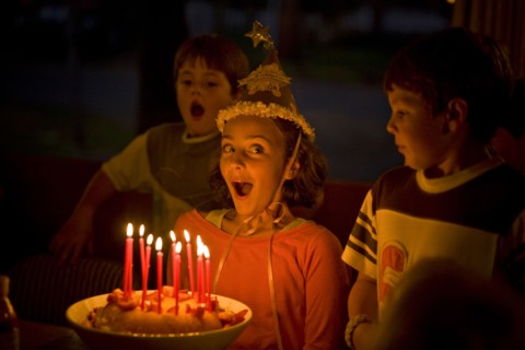 Laughing girl blowing candles on birthday cake