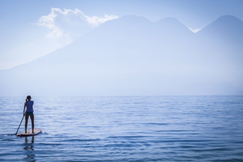 Girl standing on paddleboard in remote lake