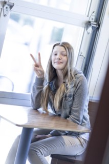 Girl giving peace sign at table