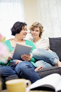 Lesbian couple using digital tablet on sofa in living room