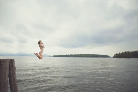 Caucasian girl jumping in remote lake