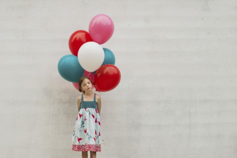 Caucasian girl holding bunch of balloons