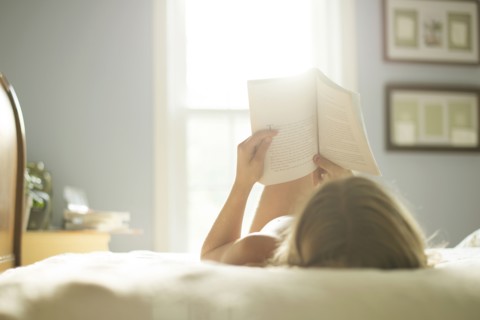 Caucasian girl reading book on bed