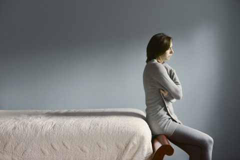 Sad Caucasian woman sitting on bed frame