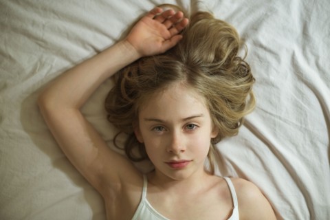Serious Caucasian girl laying on bed