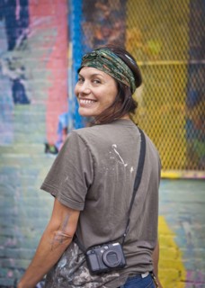 Caucasian woman with paint-splattered shirt smiling