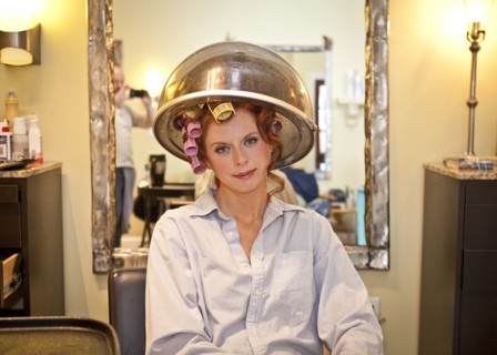Woman sitting under hair dryer in salon
