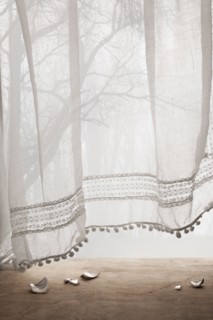 Broken ceramic shards under sheer curtains