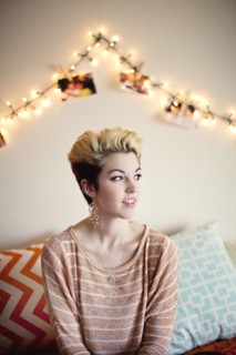 Woman sitting under string lights in bedroom