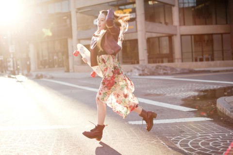 Woman carrying skateboard in city intersection