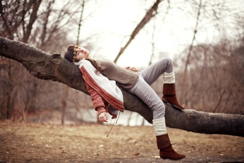 Caucasian woman laying in tree in rural field