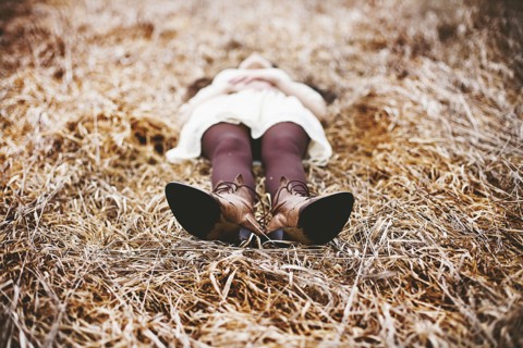 Caucasian teenage girl laying in tall grass