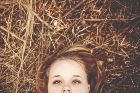 Close up of teenage girl laying in tall grass