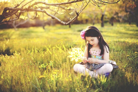 Girl playing with pinwheel in rural field
