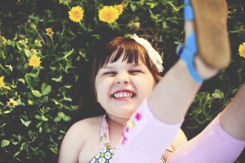 Smiling girl playing in grass with flowers