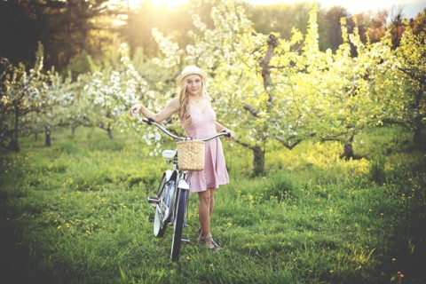 Woman pushing bicycle in rural field