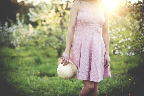 Woman holding hat in rural orchard