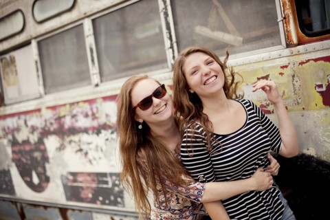 Smiling girls hugging near dilapidated bus