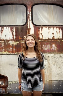 Smiling girl standing near dilapidated bus