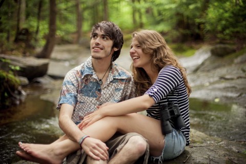 Couple sitting barefoot on boulders in forest