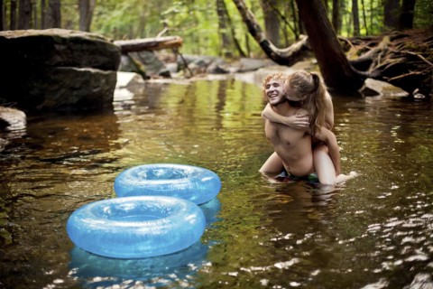 Man carrying girlfriend piggyback in forest river