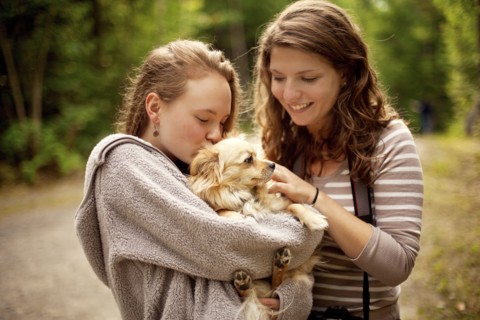 Girls petting puppy in forest