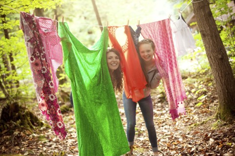 Girls hiding behind clothesline laundry in forest