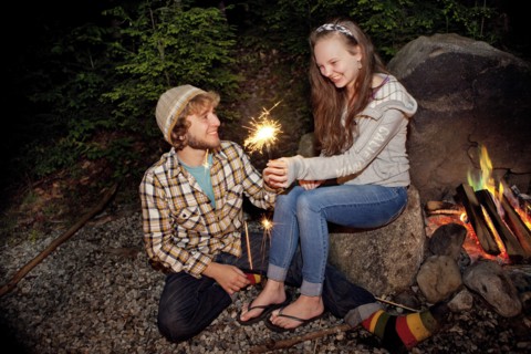 Couple playing with sparkler near campfire