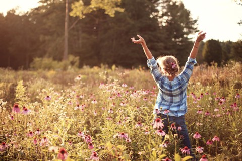 Caucasian woman cheering with arms outstretched in field