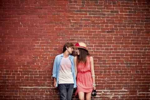 Couple leaning on brick wall