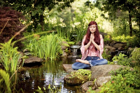Girl meditating near rural creek