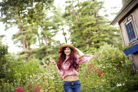 Girl wearing straw hat running in garden