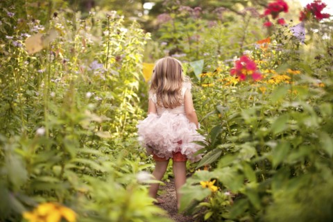Girl in frilly dress exploring tall flowers