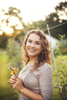 Smiling woman holding flower in garden