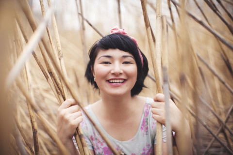 Smiling mixed race woman holding stalks in field