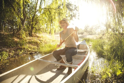 Caucasian woman rowing canoe in rural creek