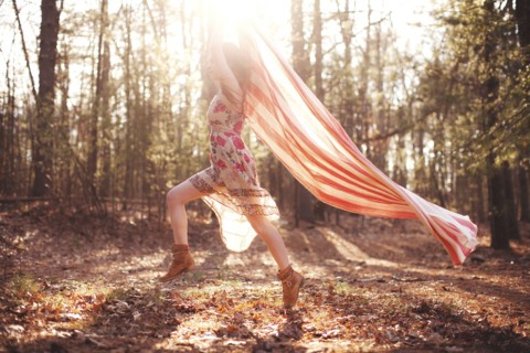Hispanic woman running with scarf in forest