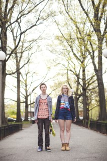 Caucasian couple standing in park with skateboard