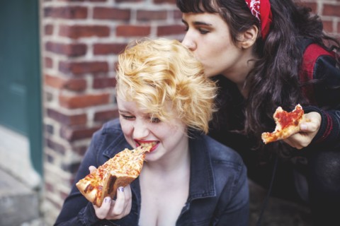 Caucasian women eating pizza outdoors