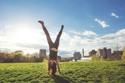 Caucasian woman doing handstand in urban park