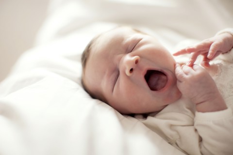 Caucasian baby girl yawning on bed