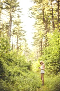 Caucasian woman walking on grass path in forest