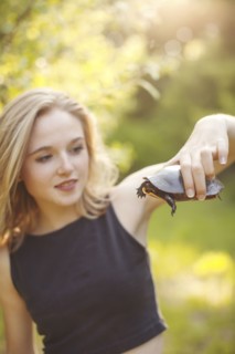 Caucasian woman examining turtle in forest