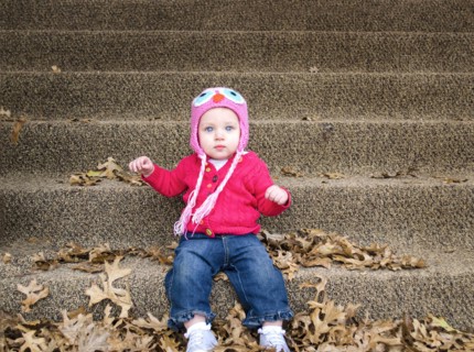 Baby girl sitting in autumn leaves on front steps