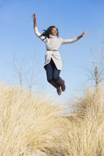 Woman jumping for joy in beach grass